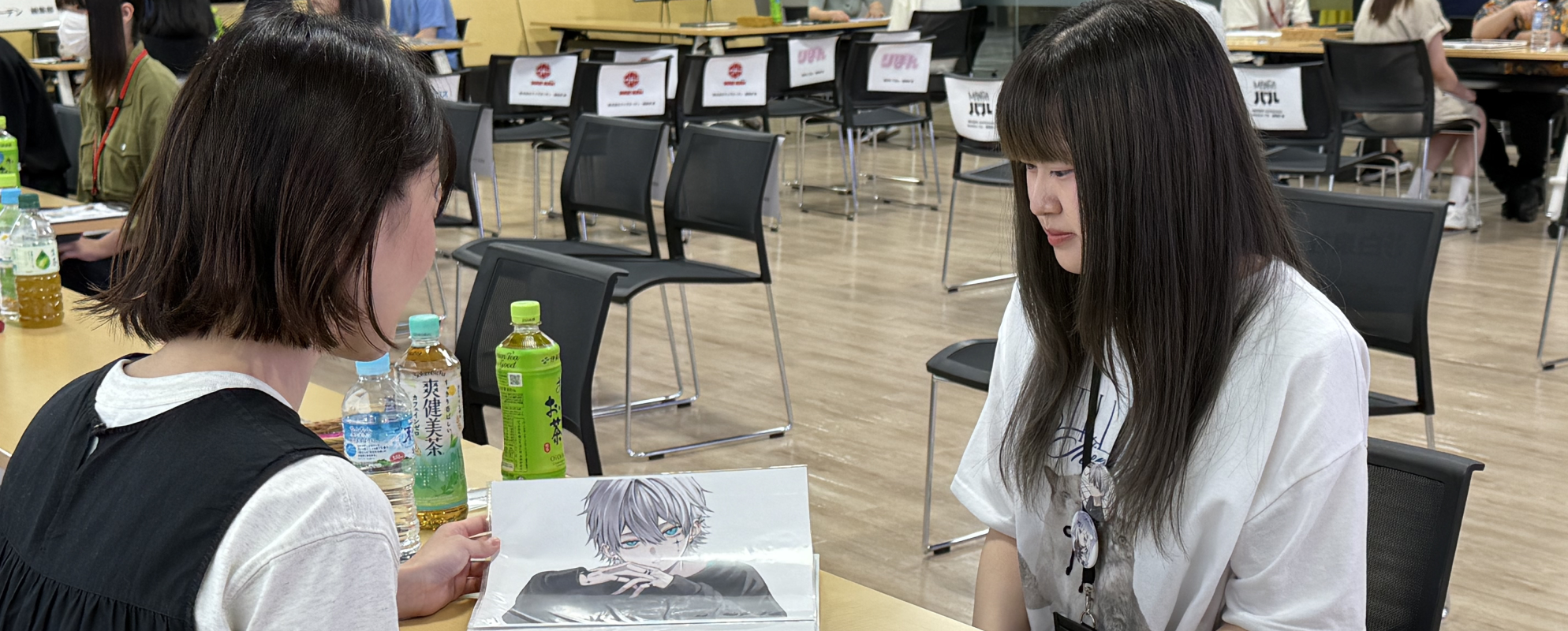業界関係者と学生が作品を見ながら話す様子